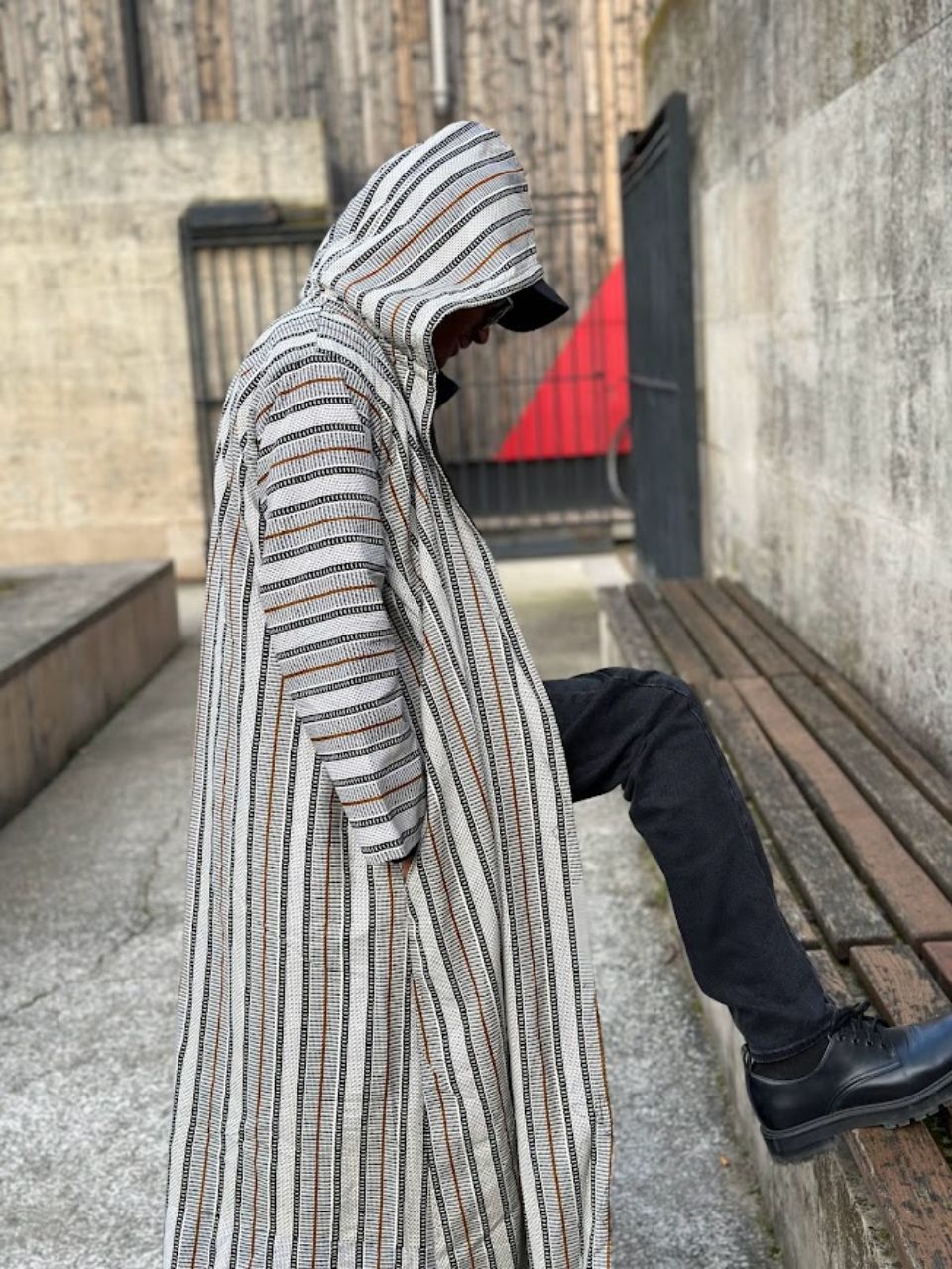 Présentant notre manteau à capuche DjidiaWax, un véritable alliage de fonctionnalité et de mode. Ce manteau long, rayé dans des tons neutres, est une pièce essentielle pour ceux qui recherchent à la fois confort et style.